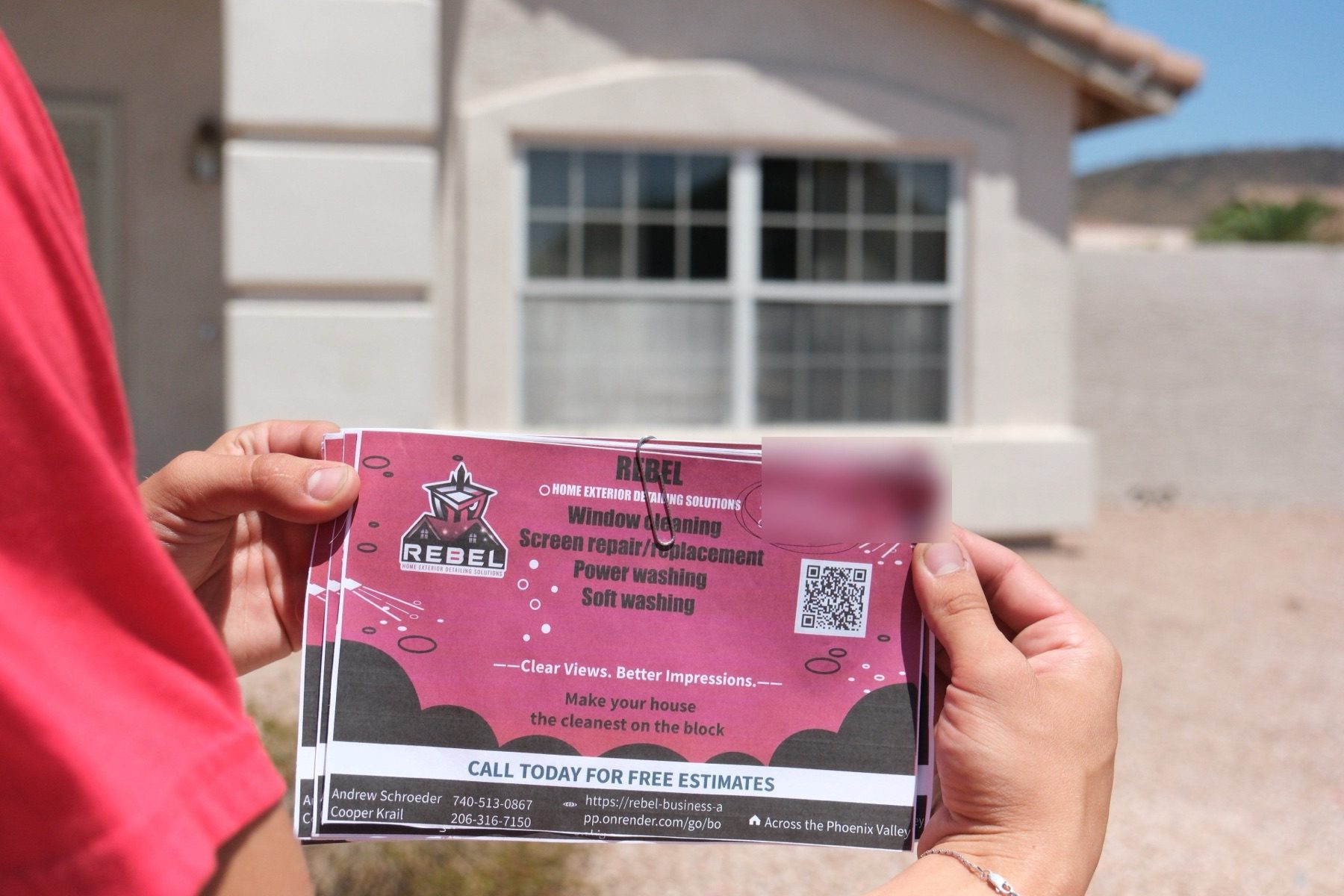 A real REBEL door-hanger flyer, held up in front of a Phoenix Valley home