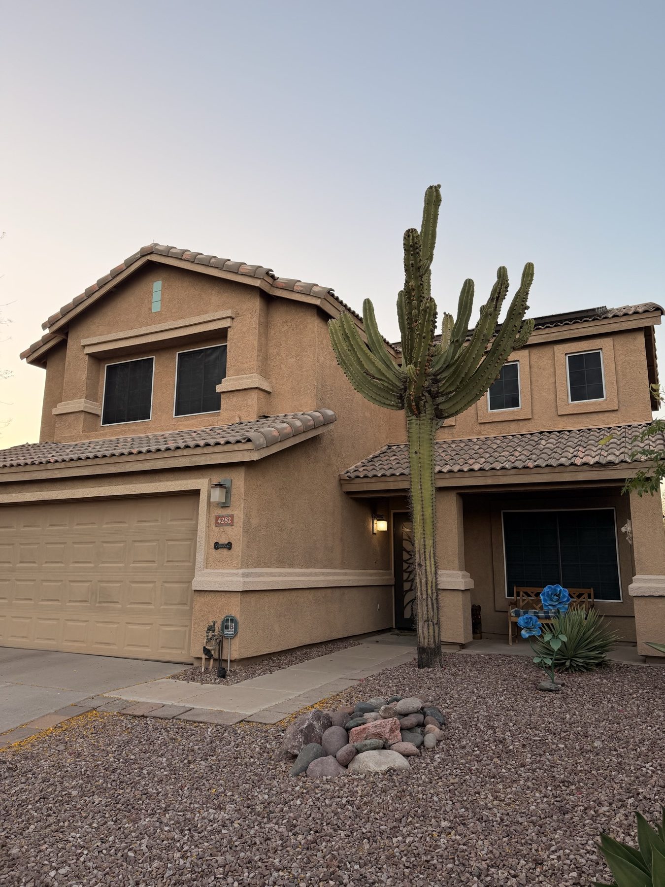 A two-story Phoenix Valley home at dusk with a saguaro cactus