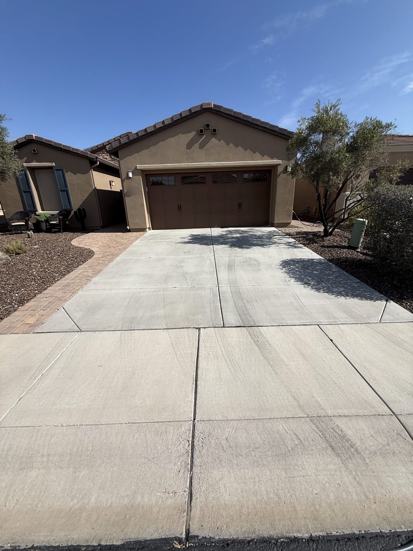 A driveway after pressure washing, the concrete an even tone under a clear sky