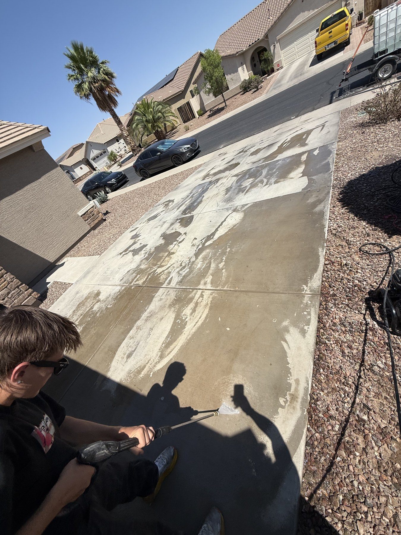 A REBEL crew member mid-pass on a driveway, the cleaned strip standing out against the surrounding concrete