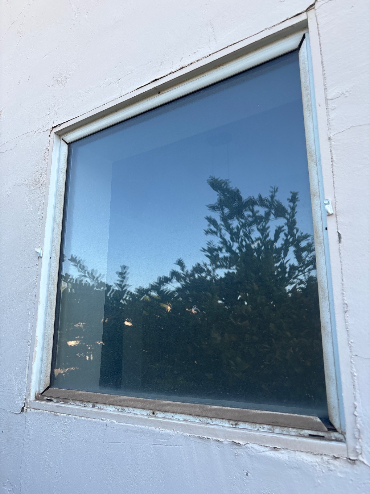 A window with a visibly dusty frame and grimy bottom track before cleaning