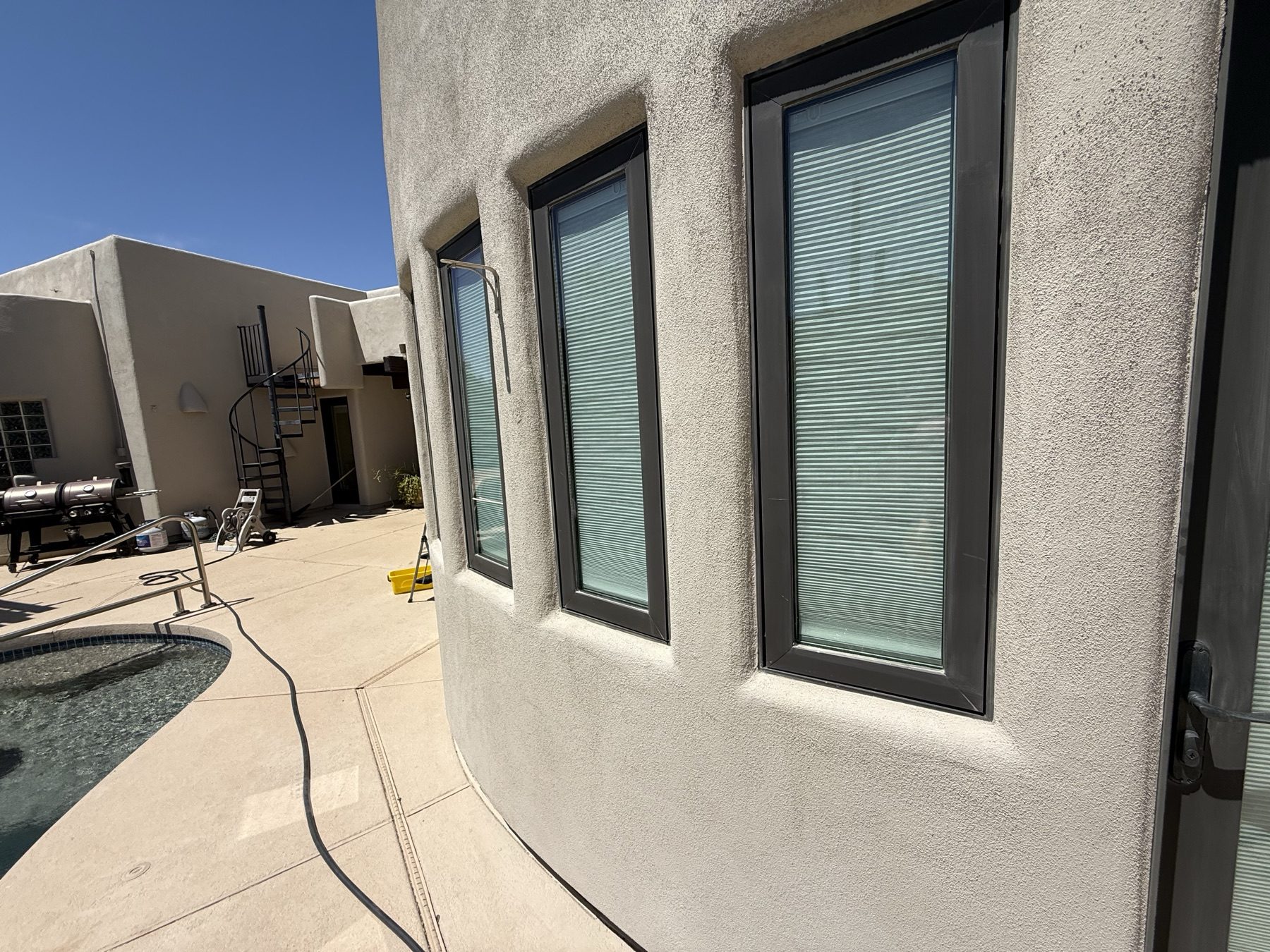 Clean windows on a curved stucco wall beside the pool
